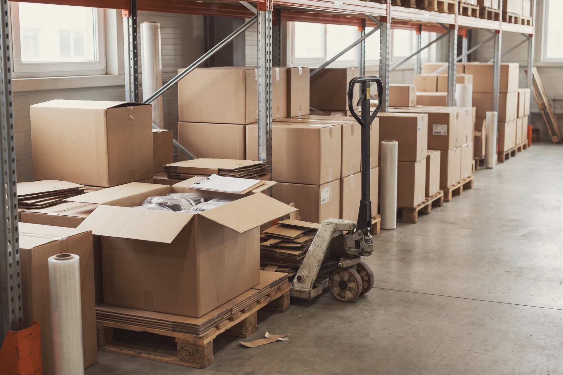 An aisle of pallets with cartons in a warehouse, one carton opened to show the goods.